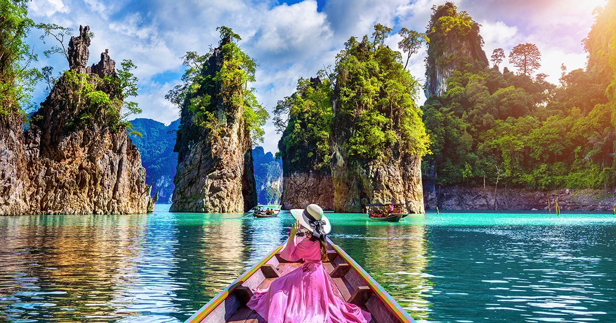 Vrouw in longtailboot tussen kalkstenen rotsen tijdens een Azië vakantie in Thailand