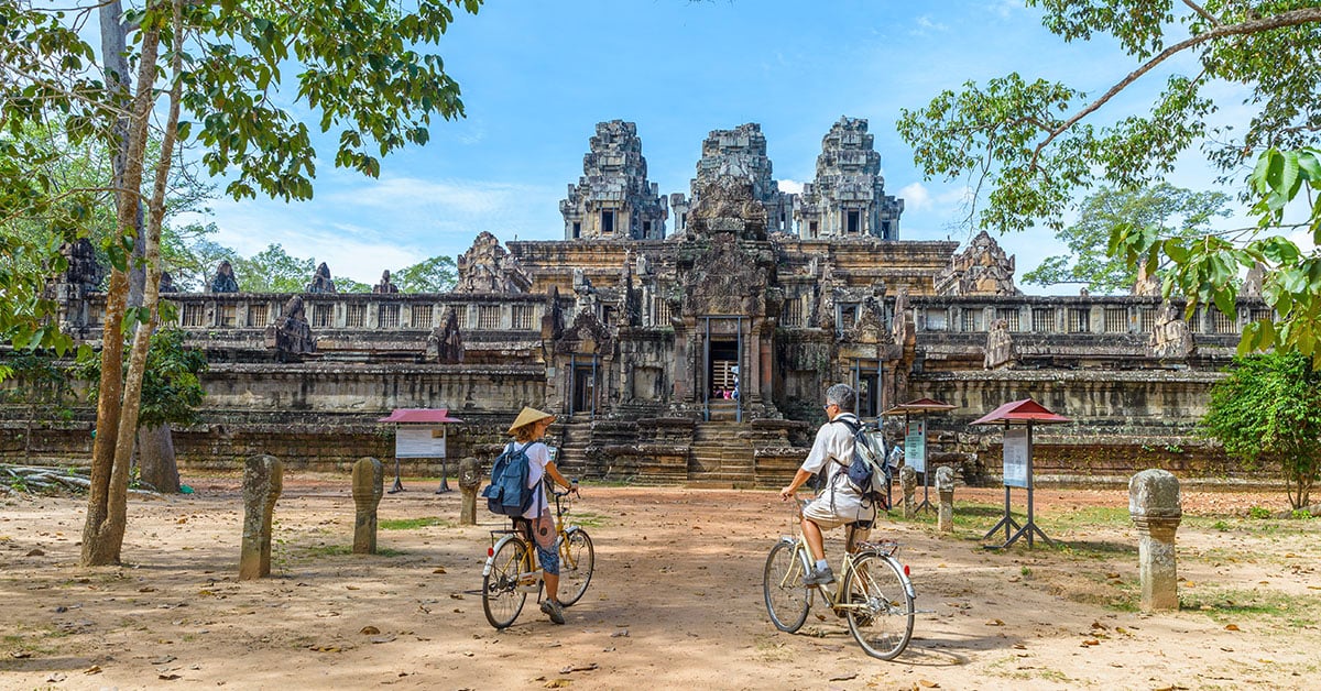 Twee reizigers fietsen naar een eeuwenoude tempel in Angkor, Cambodja – een van de hoogtepunten van een vakantie in Cambodja