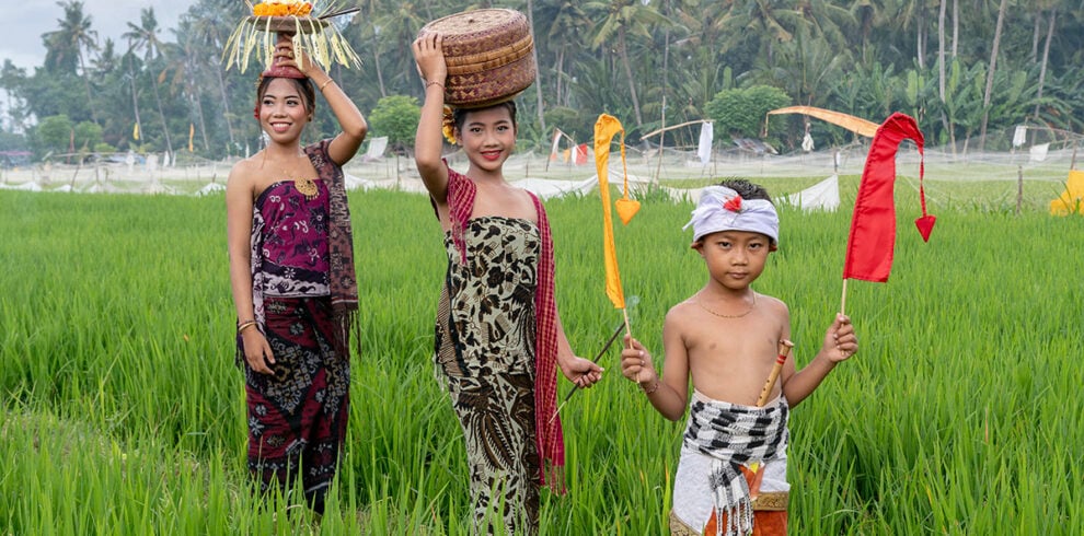 Twee Balinese vrouwen en een jongen in traditionele kleding in de rijstvelden van Bali