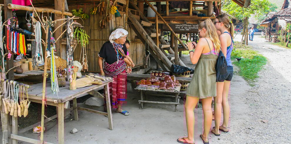2 dames staan te kijken naar een vrouw in traditionnele klederdracht