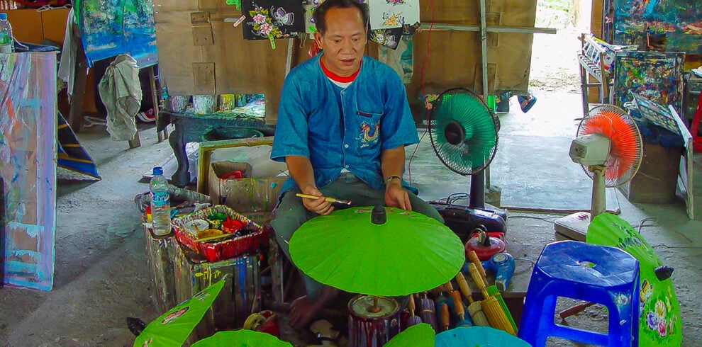 Een kunstenaar beschildert een parasol bij Bor Sang in Thailand