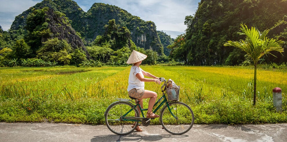 Vrouw fietst door de rijstvelden bij Tam Coc