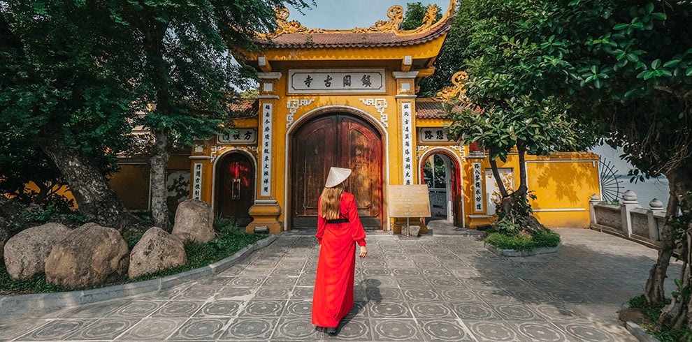 Een vrouw loopt bij de ingang van de Tran Quoc Pagoda in Hanoi