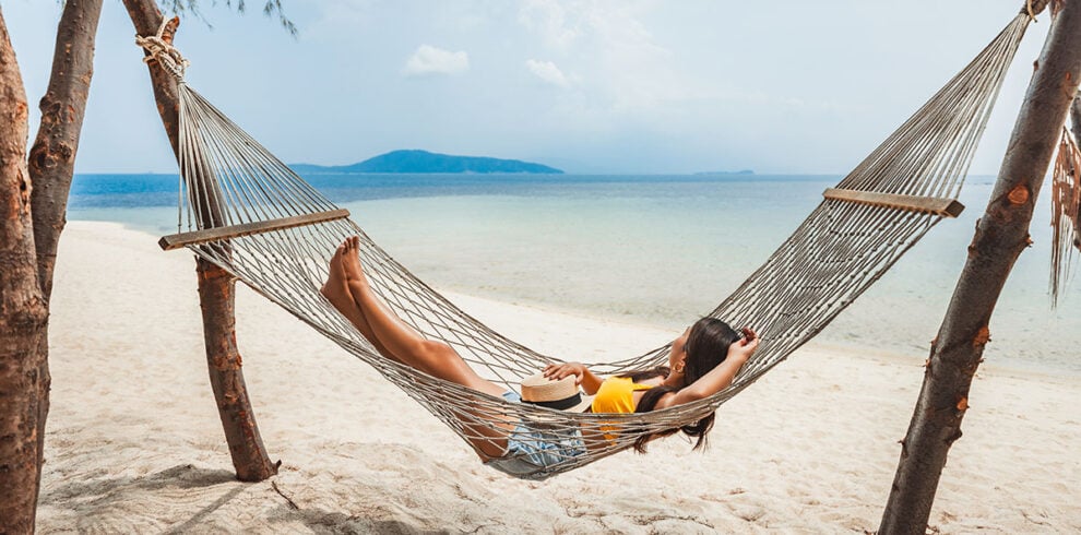 Vrouw geniet in een hangmat op een tropisch strand in Thailand