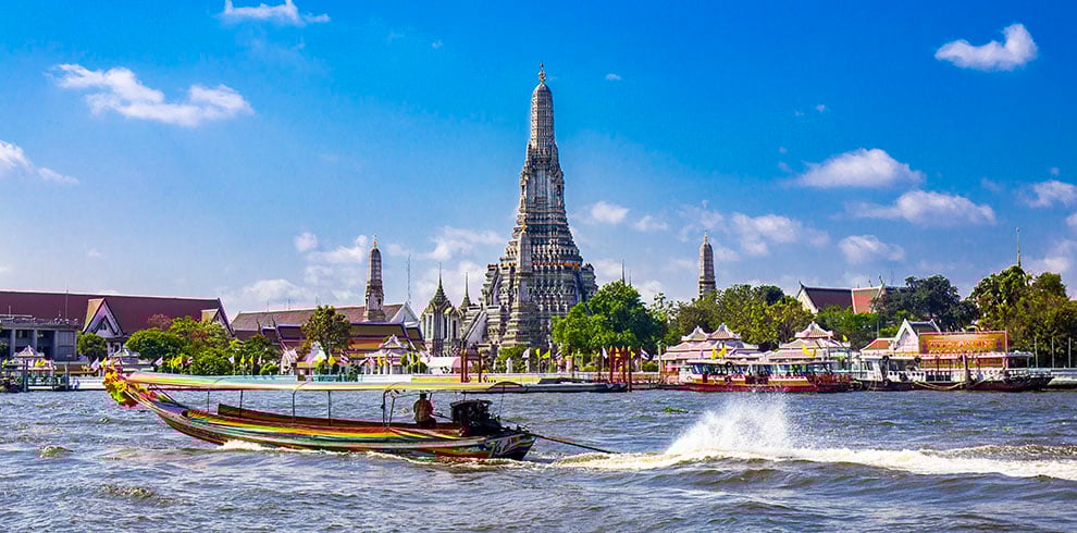 Bootjes varen over de Chao Phraya-rivier met op de achtergrond de Wat Arun