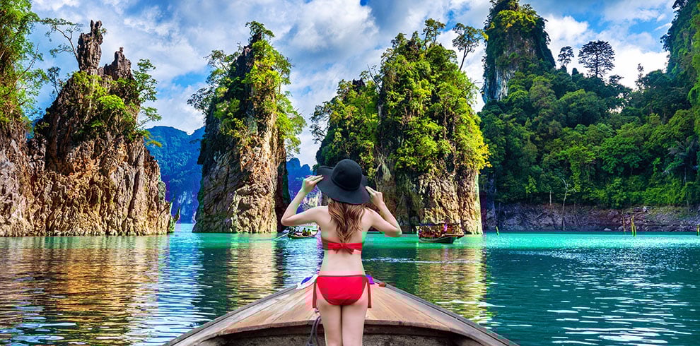 Vrouw staat in een boot en kijkt naar het prachtige landschap in het Khao Sok Nationaal Park