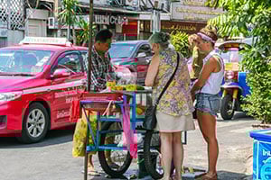Twee vrouwen kopen iets bij een kraampje op de Khao San Road in Bangkok