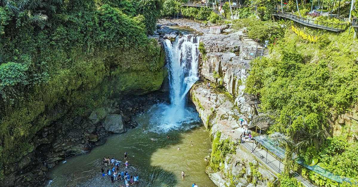 Mensen zwemmen bij de Tegenungan waterval bij Ubud omringd door groene jungle