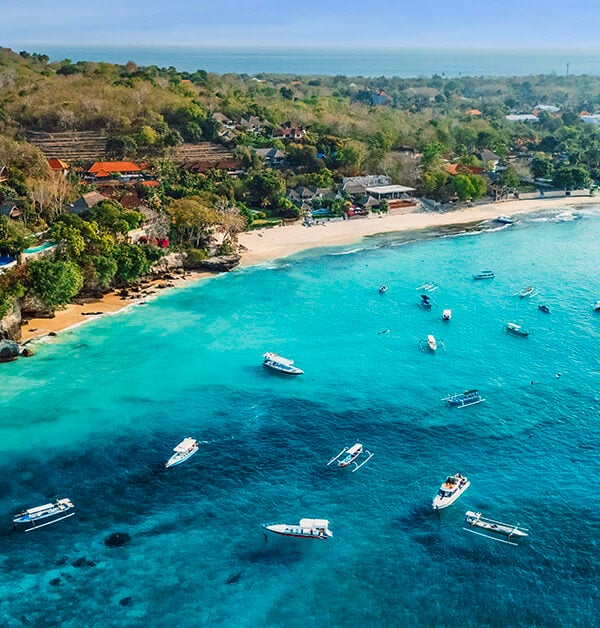 Uitzicht vanuit de lucht op de kust van Nusa Lembongan met turquoise zee en boten voor de kust