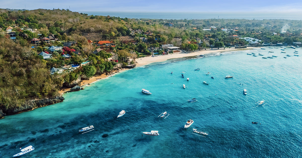 Uitzicht vanuit de lucht op de kust van Nusa Lembongan met turquoise zee en boten voor de kust