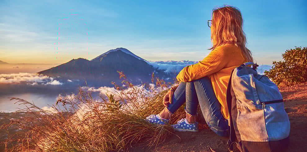 Vrouw geniet van de zonsopkomst vanaf de top van Mount Batur tijdens de rondreis Verken Bali in Stijl