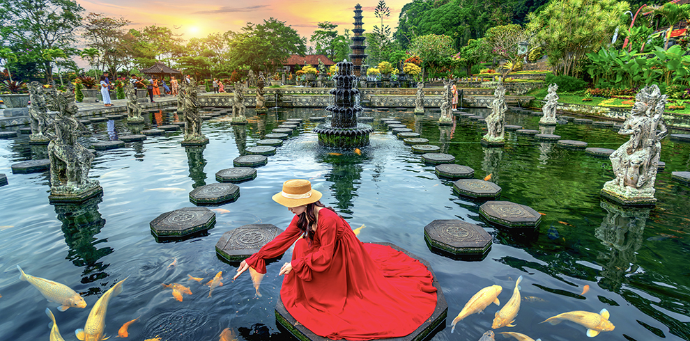 Vrouw voert de vissen bij de Tirta Gangga op Bali