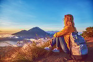 Een vrouw geniet van de zonsopkomst op de top van Mount Batur, Bali
