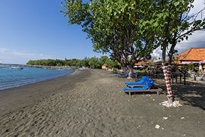 Het zwarte zandstrand bij het Adi Assri Beach Resort in Pemuteran, Bali