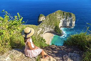 Vrouw kijkt uit op Kelingking Beach vanaf het viewpoint op Nusa Penida, Bali