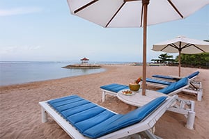De ligbedden met parasols op het strand bij het Respati Beach Hotel in Sanur