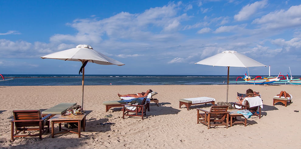 Parasols en strandbedjes op het strand van Sanur Beach, Bali