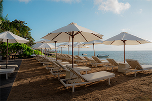 Ligbedden en parasols op het strand bij Griya Santrian in Sanur, Bali