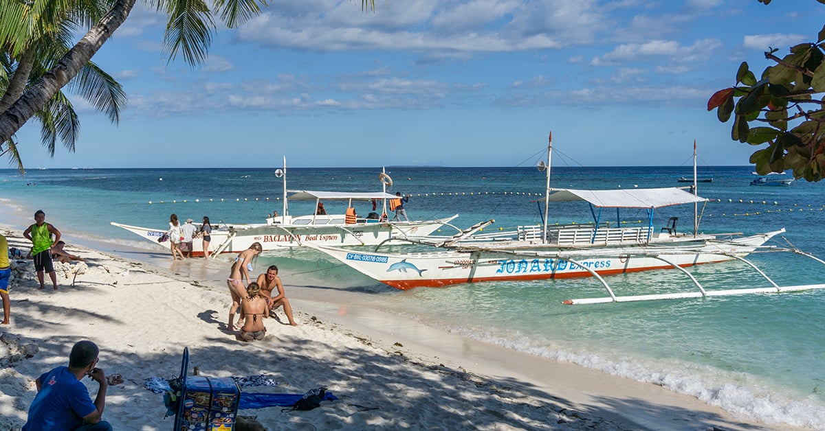 Traditionele boten en toeristen op Alona Beach, Bohol