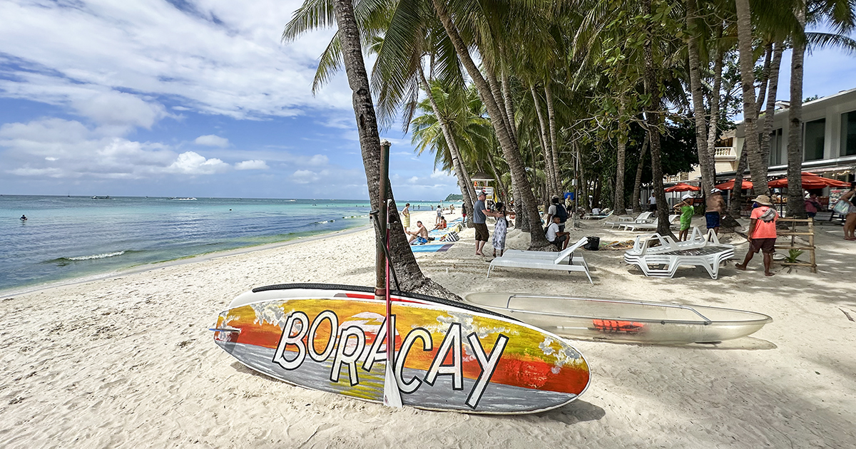 Paddleboards en ligbedden staan klaar voor verhuur op het witte zandstrand van White Beach op Boracay.