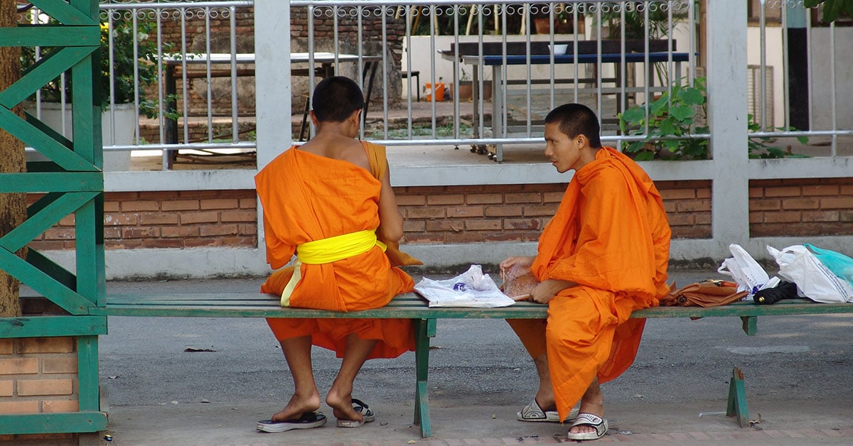 Twee monniken in oranje gewaden op een bankje in het historische centrum van Chiang Mai