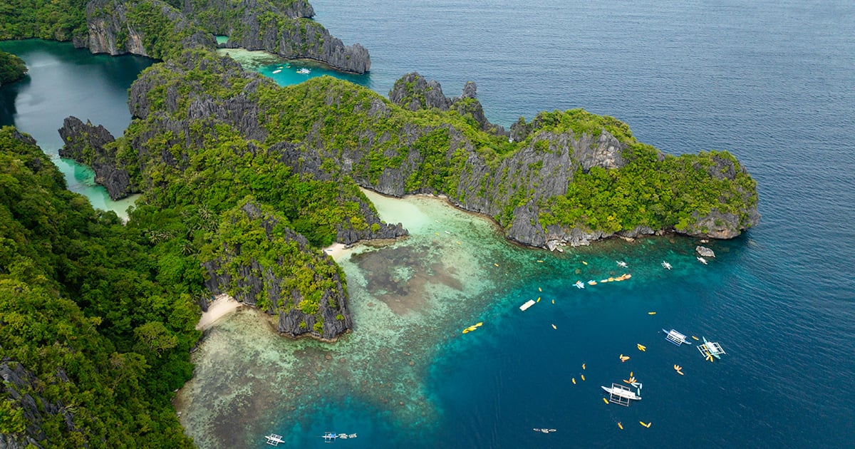 Luchtfoto van Big Lagoon op Miniloc Island met traditionele bootjes in het turquoise water bij El Nido, Filipijnen.
