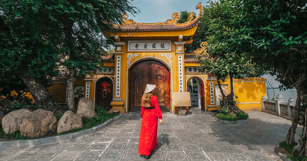Een vrouw in traditionele Vietnamese kleding bij de Tran Quoc Pagoda in Hanoi, Vietnam.