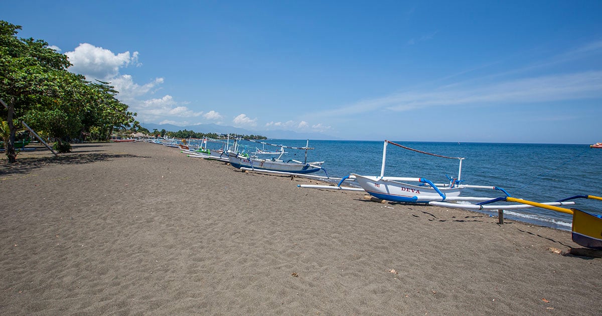 Traditionele houten bootjes liggen op het zwarte zandstrand van Lovina, Bali.