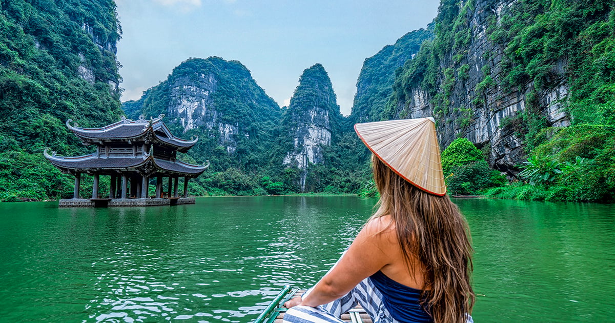 Een Vietnamese vrouw op een boot door het karstgebergte in Ninh Binh, Vietnam