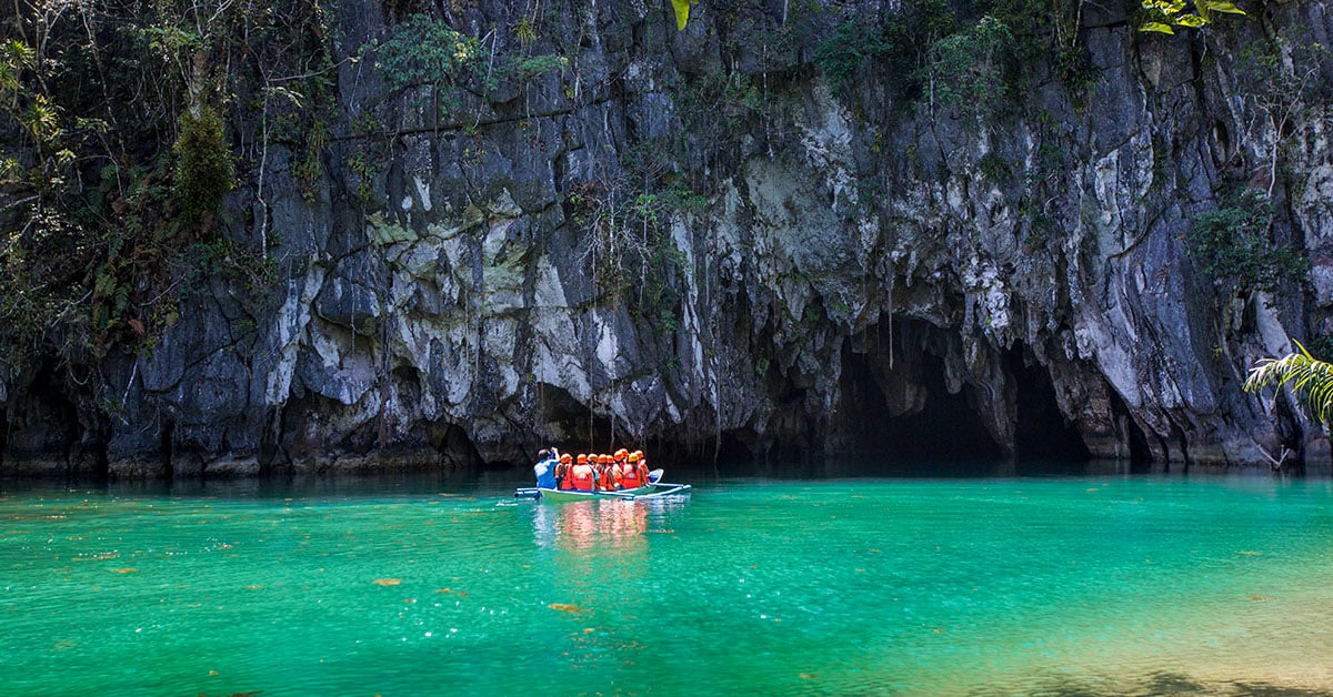 Een groep toeristen vaart per boot door het kustwater van Sabang op weg naar de ingang van de grot van de Puerto Princesa Underground River