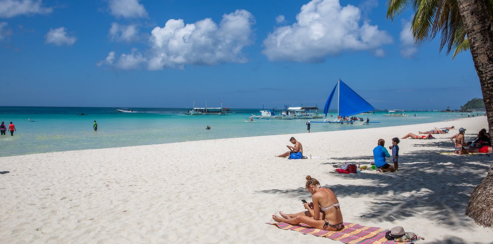 Toeristen genieten van zon, zee en strand op White Beach, het beroemde zandstrand van Boracay in de Filipijnen.