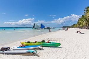 Kano’s en paddleboards te huur op het prachtige White Beach op Boracay, Filipijnen, met helder turquoise water en wit zandstrand.