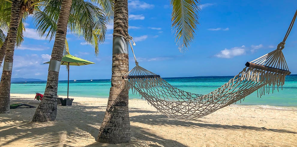 Een hangmat onder een palmboom op een tropisch strand in de Filipijnen.