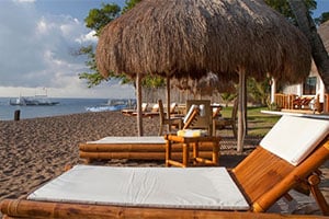 Ligbedden en parasols op het strand bij het Pura Vida Beach and Dive Resort in Dauin.