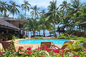 Zwembad van White Villas Resort op Siquijor met uitzicht op de azuurblauwe zee, omringd door palmbomen en een tropische, ontspannen sfeer.
