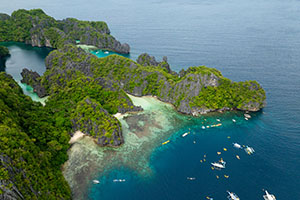 Luchtfoto van Miniloc Island met de turquoise wateren van de Big Lagoon, omringd door kalkstenen kliffen.