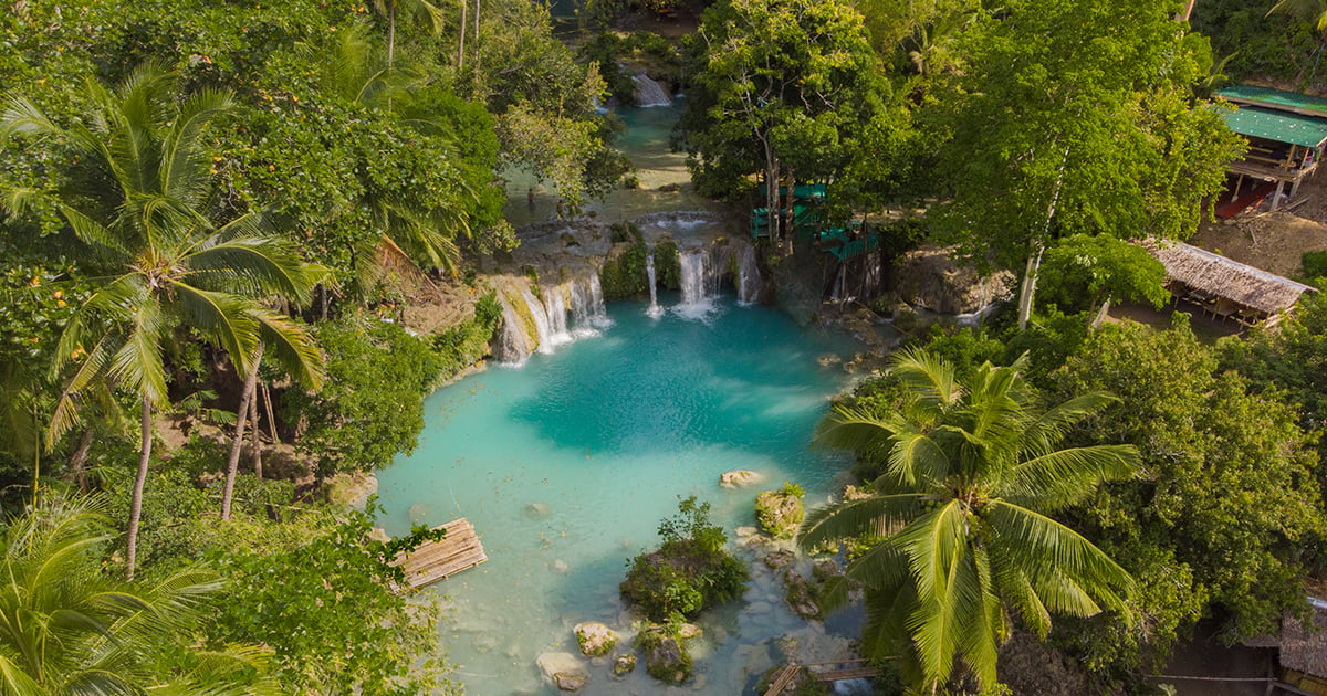 Luchtfoto van de turquoise lagen watervallen van Cambugahay Falls op Siquijor, omringd door tropisch groen.