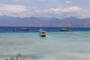 Bootjes in het heldere water bij Gili Trawangan met bergen op de achtergrond