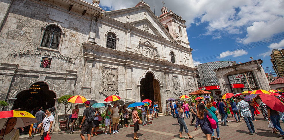 Toeristen en gelovigen op een warme dag bij de Basilica del Santo Nino in Cebu City.