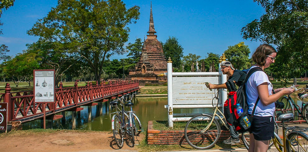 Toeristen op de fiets bij de Wat Sa Si in het Sukhothai Historical Park