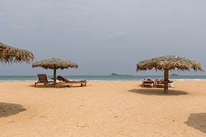Parasols en ligbedden op het strand bij het Pigeon Island Beach Resort in Nilaveli